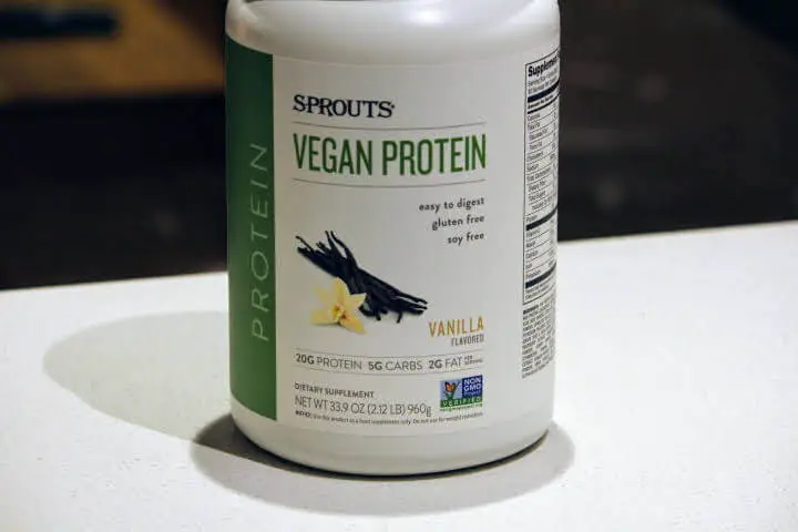 Sprouts Vegan Protein Powder 33.9 oz container sitting on kitchen countertop